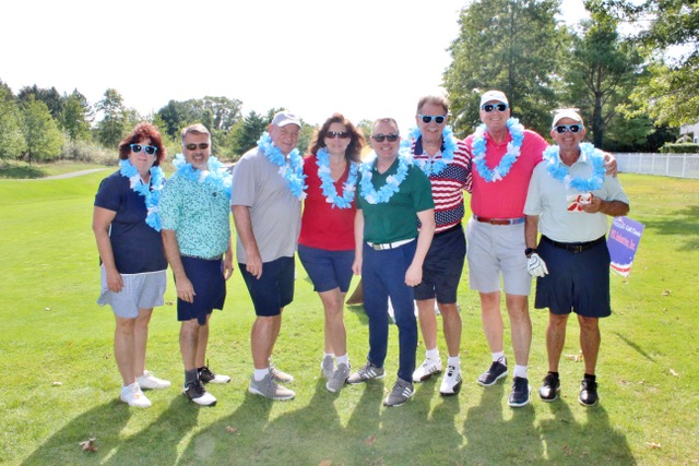 Participants wearing leis on the fairway, posing for a photo